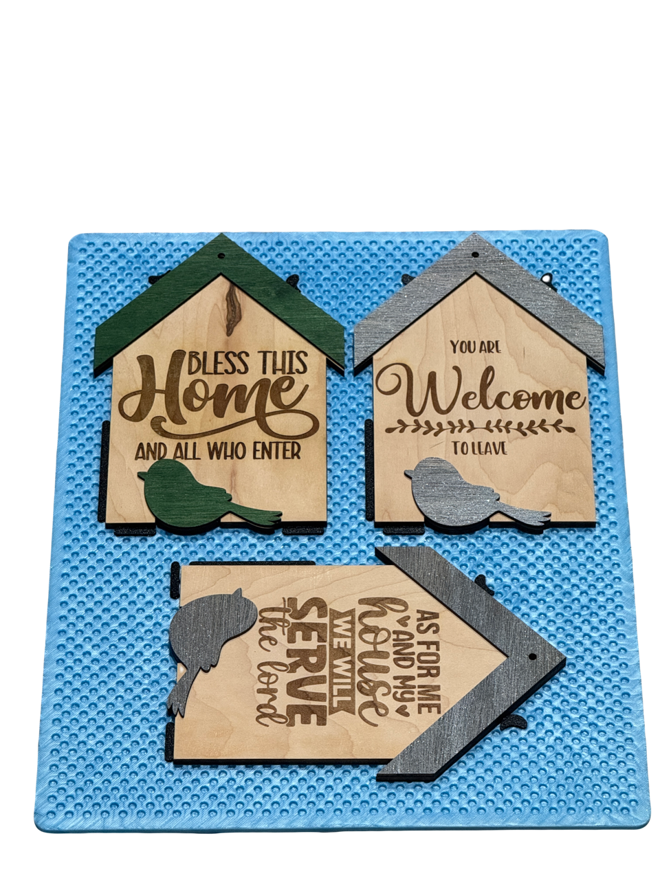 Jiggit blue silicone mat holding three engraved wooden birdhouse signs at different angles