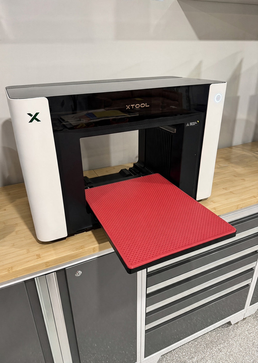 Red Jiggit silicone mat seated on the print bed of an xTool O1 Omni 4-in-1 UV printer