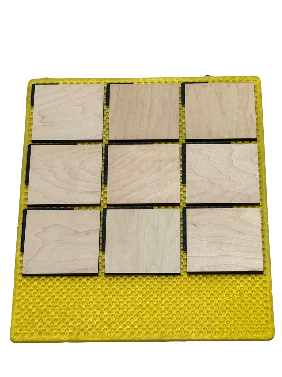 Jiggit yellow silicone mat holding nine identical square wooden blanks in a three by three grid